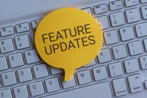 Yellow speech bubble reading FEATURE UPDATES on keyboard
